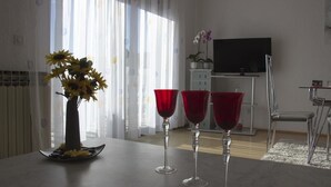 A dining area with a table set for two, featuring a vase with flowers and two red wine glasses. - Apartment Marija (Kastela)