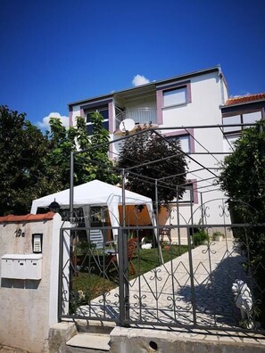A two-story house with a white facade, a balcony, and a satellite dish. - Apartment Marija (Kastela)