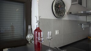 A kitchen with a clock, a bottle, and wine glasses on the counter. - Apartment Marija (Kastela)