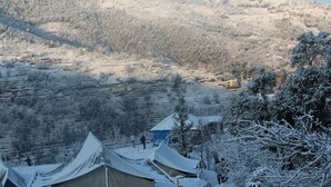 Un paisaje nevado con tiendas de campaña y algunos edificios, probablemente una zona de alojamiento aislada.