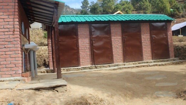 Un edificio de ladrillo con techo verde y un porche con puerta metálica.