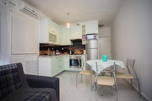 A compact kitchen with a dining area, a sofa, and a view of a cityscape at night.