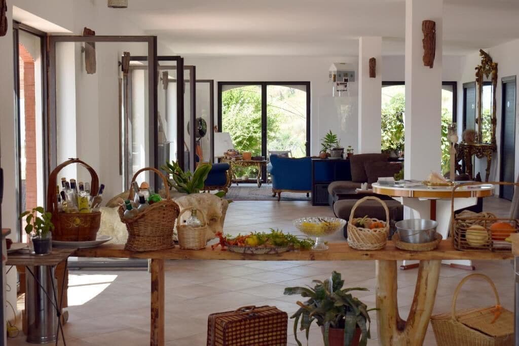 Un'ampia zona giorno con un tavolo grande apparecchiato per la cena, un divano e una poltrona blu.