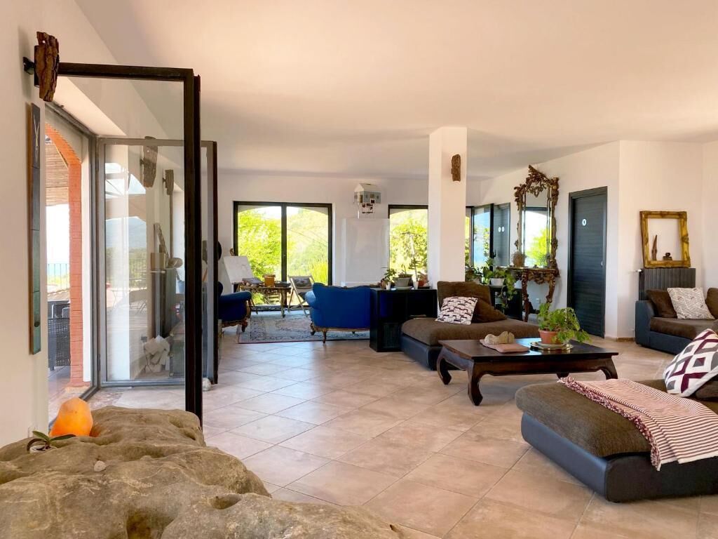 A spacious living area with a glass door leading to a balcony, a blue armchair, a brown sofa, and a coffee table.