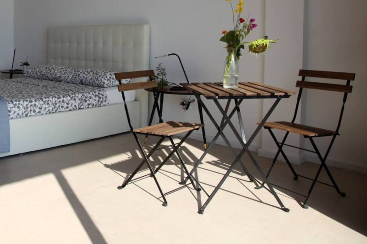 Une chambre à coucher avec un lit, une petite table et des chaises, et une fenêtre donnant sur un beau paysage.