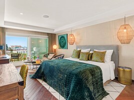 Een moderne hotelkamer met een groot bed, een balkon en uitzicht op de stad.