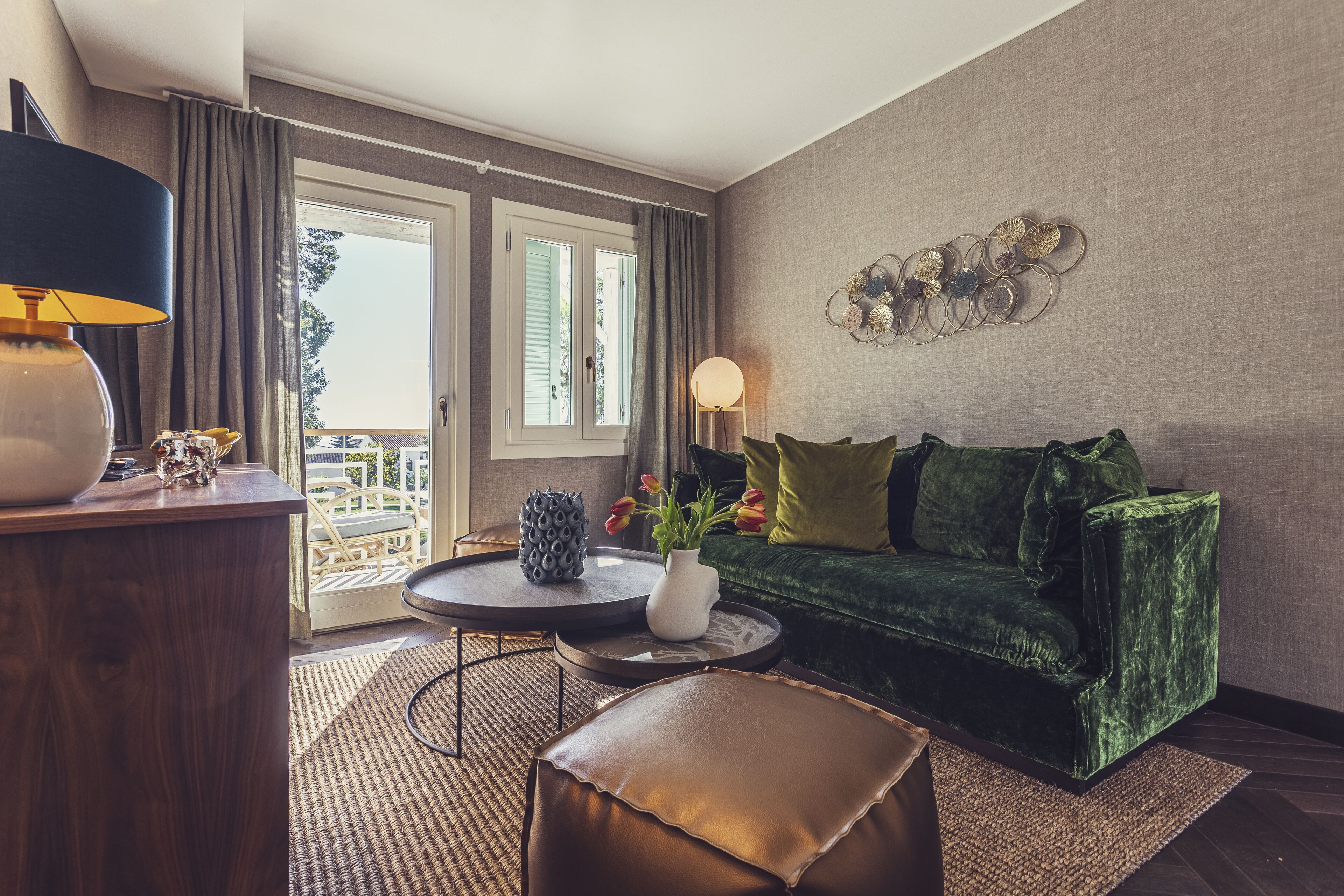 Un salon avec un canapé en velours vert, une table basse en bois, une lampe et un élément décoratif mural.