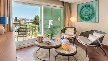 Una camera d'hotel con un balcone, un tavolo da pranzo, due sedie, una lampada e un quadro appeso al muro.