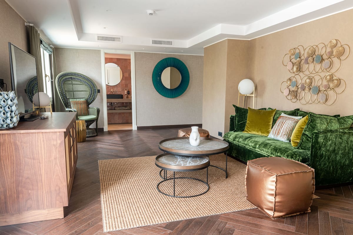 A modern living room with a wooden coffee table, a green sofa, and a round mirror on the wall.
