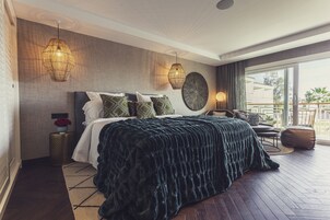 Een slaapkamer met een groot bed, een ronde decoratie aan de muur en uitzicht op het landschap door een schuifdeur van glas.