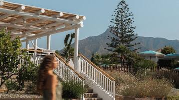 Una mujer caminando por un sendero de piedra con una pérgola y escaleras al fondo.