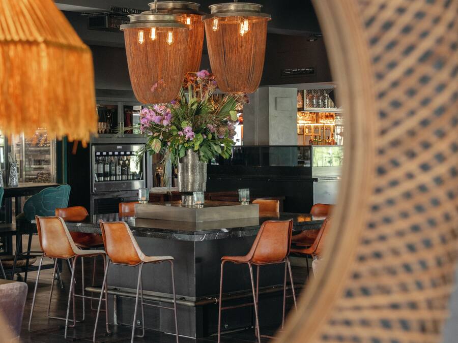 A modern kitchen with a central island, bar stools, and hanging pendant lights.