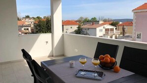 A balcony with a table set for two, featuring a bowl of oranges and glasses of orange juice. - Apartments Milic (Kastela)