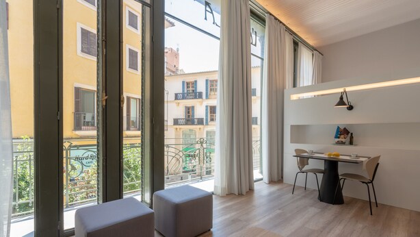 Un appartement moderne doté de grandes fenêtres, d’un coin repas et d’un balcon.
