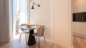 Une cuisine moderne avec des meubles blancs, un plan de travail noir et une fenêtre ornée de rideaux légers.