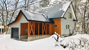 Una casa moderna con tetto a falda, rivestimento in legno e un garage.