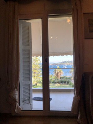 A room with a sliding glass door leading to a balcony with a view of the sea and boats. - Luxury Apartment Sea View Garden Parking (Corfu)