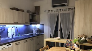 Eine moderne Küche mit Holzschränken, einem eingebauten Geschirrspüler, einer Kaffeemaschine und einem Essbereich mit Tisch und Stühlen.
