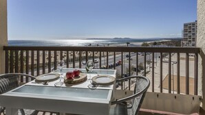 A balcony with a table set for two, overlooking a beach and a parking lot. - Nice apartment for 3 guests with A/C, WIFI, TV, patio and pets allowed (Empuriabrava)