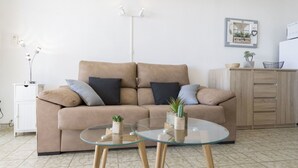 A living room with a beige sofa, two glass tables, and a wooden cabinet. - Nice apartment for 3 guests with A/C, WIFI, TV, patio and pets allowed (Empuriabrava)