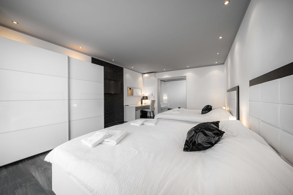 A modern hotel room with a large bed, a desk, and a mirror.