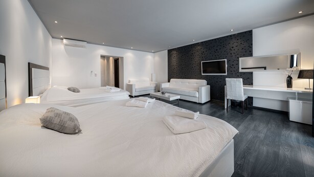 Ett modernt hotellrum med en stor säng, två soffor, ett skrivbord och en TV.