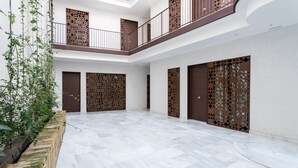 Un'ampia area interna con pavimento in marmo, diverse porte e un balcone con ringhiera.