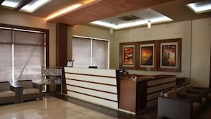 A reception area with a counter, seating, and artwork on the walls. - Hotel Regency (Varanasi)