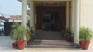 A building entrance with a set of steps leading up to a door, flanked by potted plants. - Hotel Regency (Varanasi)