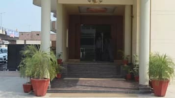 A building entrance with a set of steps leading up to a door, flanked by potted plants.
