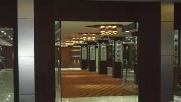 A modern hotel lobby with a carpeted floor, glass walls, and a chandelier. - Hotel Regency (Varanasi)