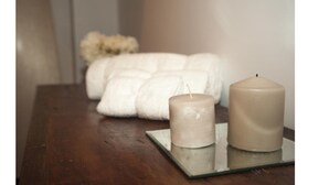 Two candles on a reflective surface with a white towel in the background. - Da Molly (Rome)