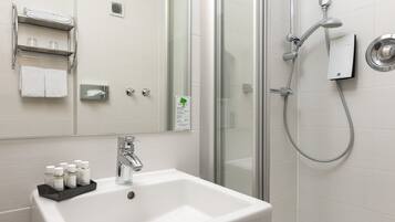 A bathroom with a white sink, a glass shower enclosure, and a towel rack with folded towels.