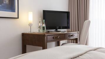 Een hotelkamer met een bed, een houten nachtkastje met een televisie, een lamp en twee waterflessen.