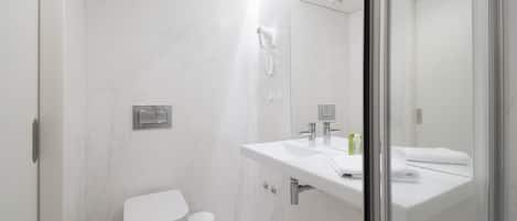 Uma casa de banho moderna com sanita, bidé e zona de duche com divisória de vidro.