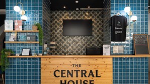 A reception area with a wooden counter labeled "The Central House," a flat-screen TV, and various informational posters.