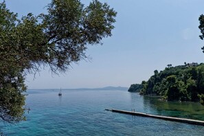 Un lac paisible, avec un quai et un voilier qui se dessine à l'horizon.