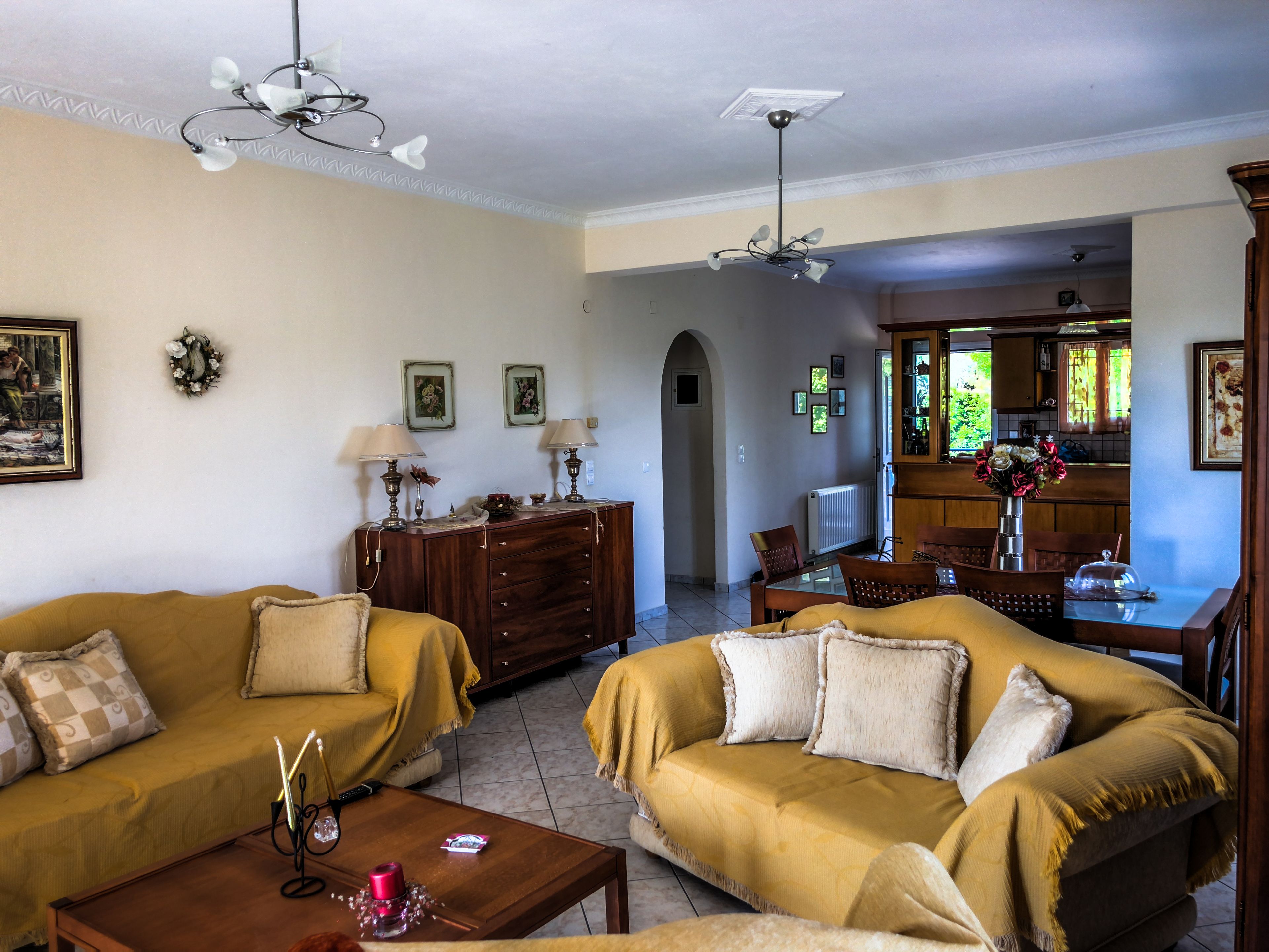 Uma sala de estar com dois sofás, uma mesa de centro, uma televisão e um espaço de refeições com cadeiras e mesa.
