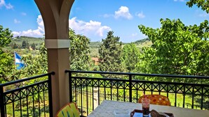 A balcony with a table set for two, a flag, and a view of the countryside. - Hidden gem in nature reserve on the beach (Corfu)