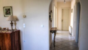 A hallway with a wooden cabinet, a table, and a door at the end. - Hidden gem in nature reserve on the beach (Corfu)