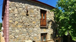 A stone building with a wooden balcony and a window with a wooden shutter. - Tas Suite Konukevi (Gökçeada)