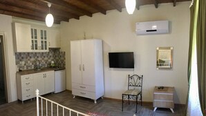 A bedroom with a bed, a small bedside table, a chair, and a TV. - Tas Suite Konukevi (Gökçeada)