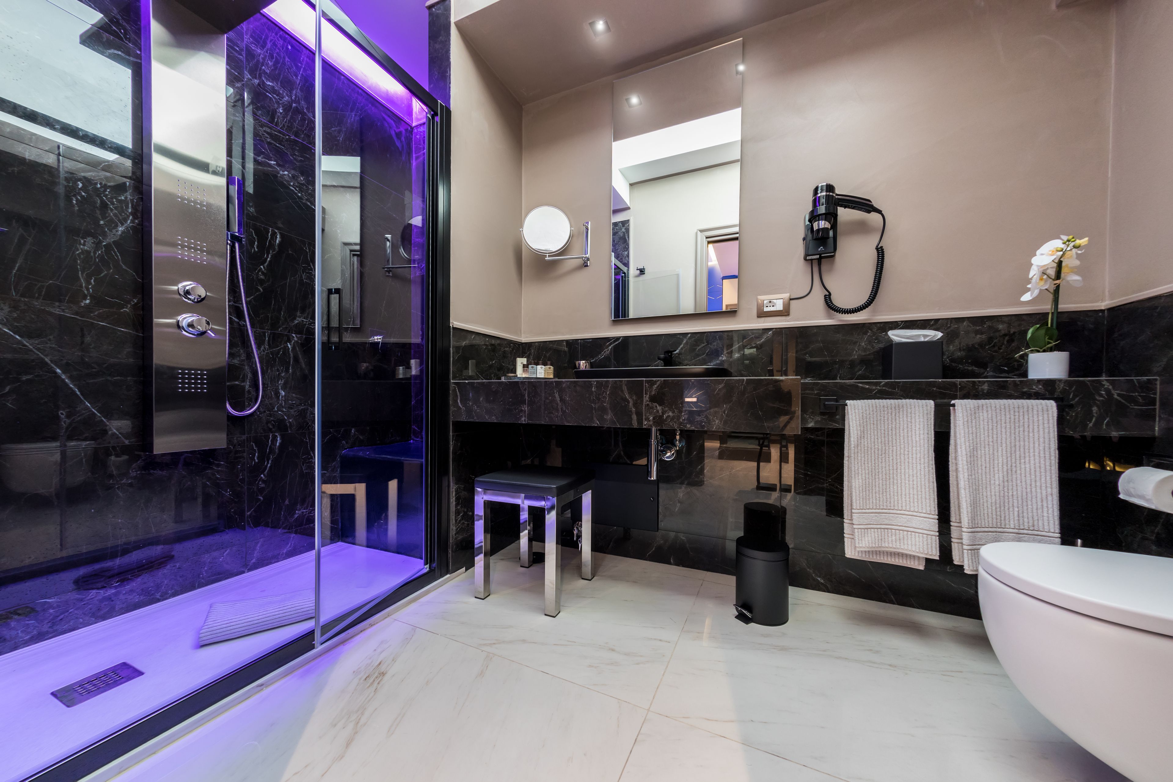 A modern bathroom with a glass-enclosed shower, a vanity with a mirror, and a toilet.