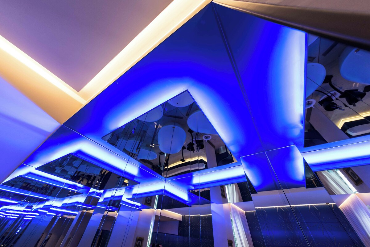 Un interior moderno con diseño geométrico en el techo y superficies reflectantes.