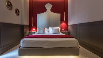 Una habitación de hotel moderna con una cama grande, paredes rojas de acento y un cabecero decorativo.
