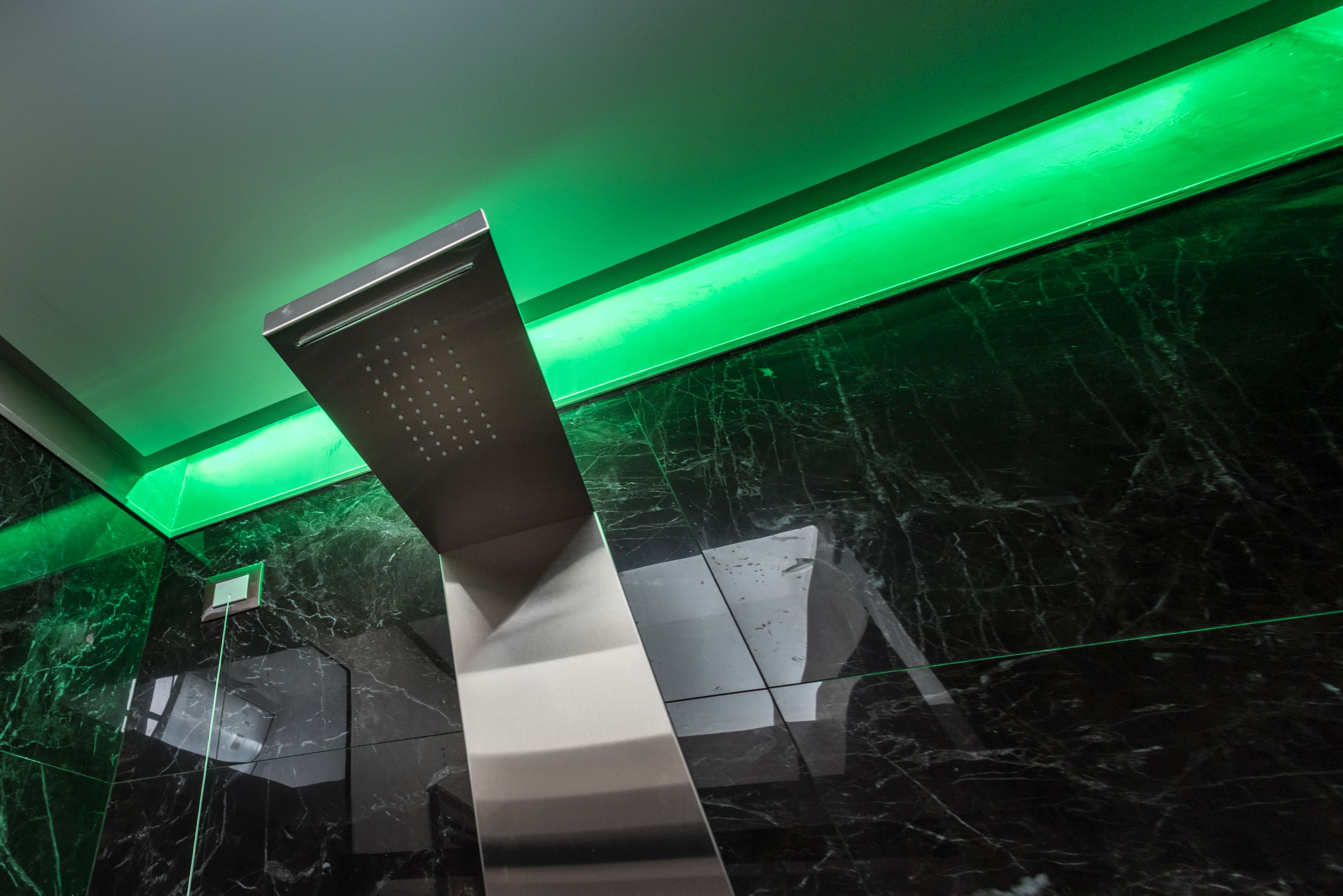 A modern elevator with a metallic finish and green lighting.