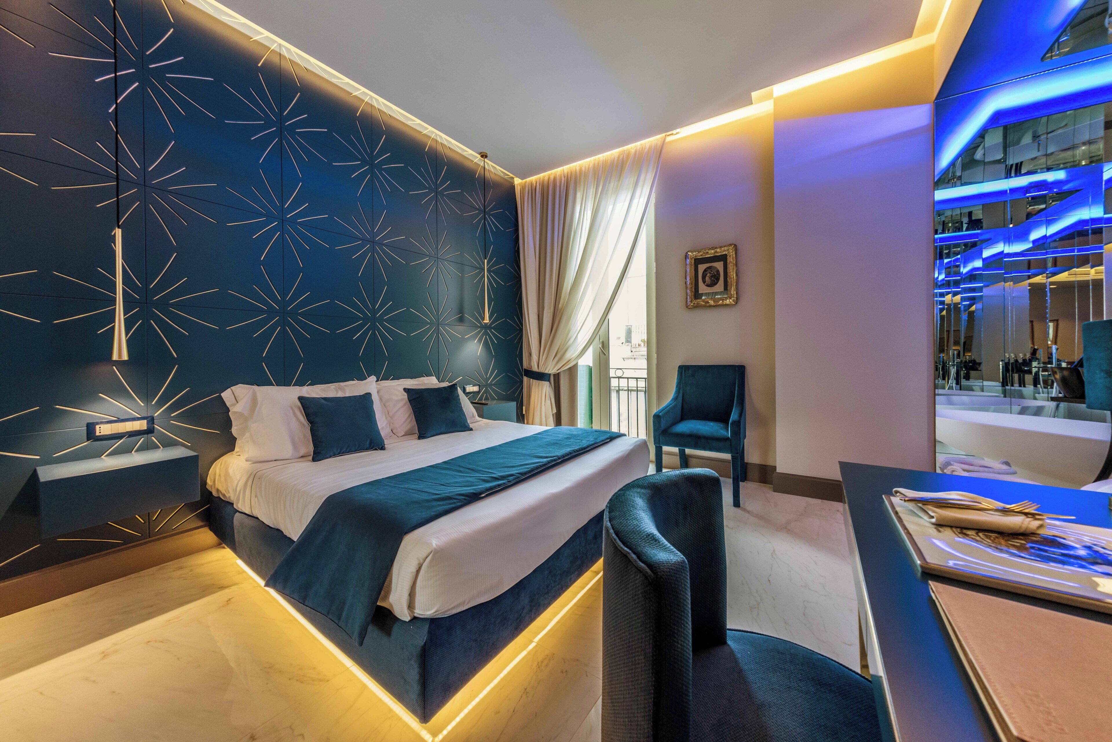 Una habitación de hotel moderna con cama, mesita de noche, sillón y escritorio con silla.