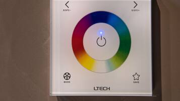 Panel de control con una rueda de color, flechas direccionales y botones etiquetados 'MODE' y 'SAVE' para un dispositivo de iluminación.