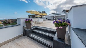 Una terraza en la azotea con asientos al aire libre, plantas en macetas y vistas de la ciudad.