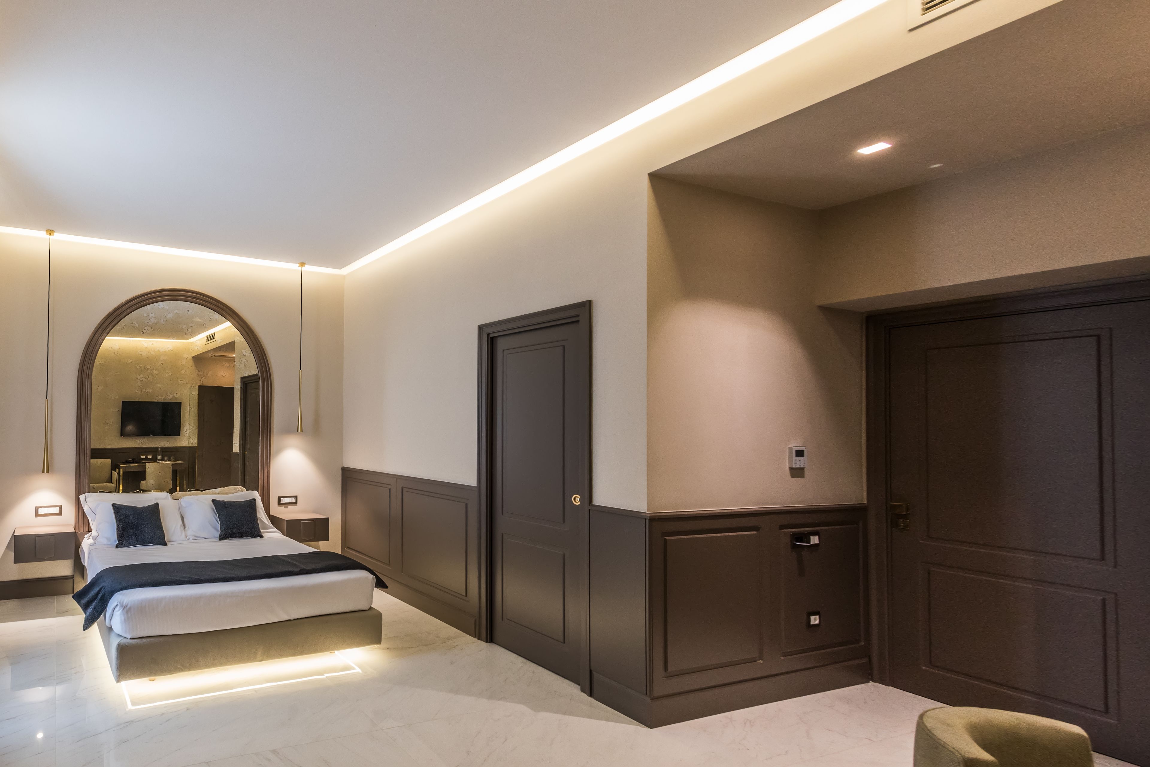 A modern bedroom with a large bed, built-in wardrobes, and a television in the background.